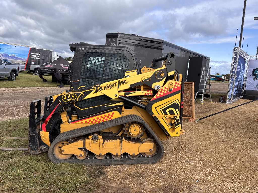 CAT 259D3 compact track loader fully wrapped in a bold custom Deviant Ink design with yellow, red, and black graphics